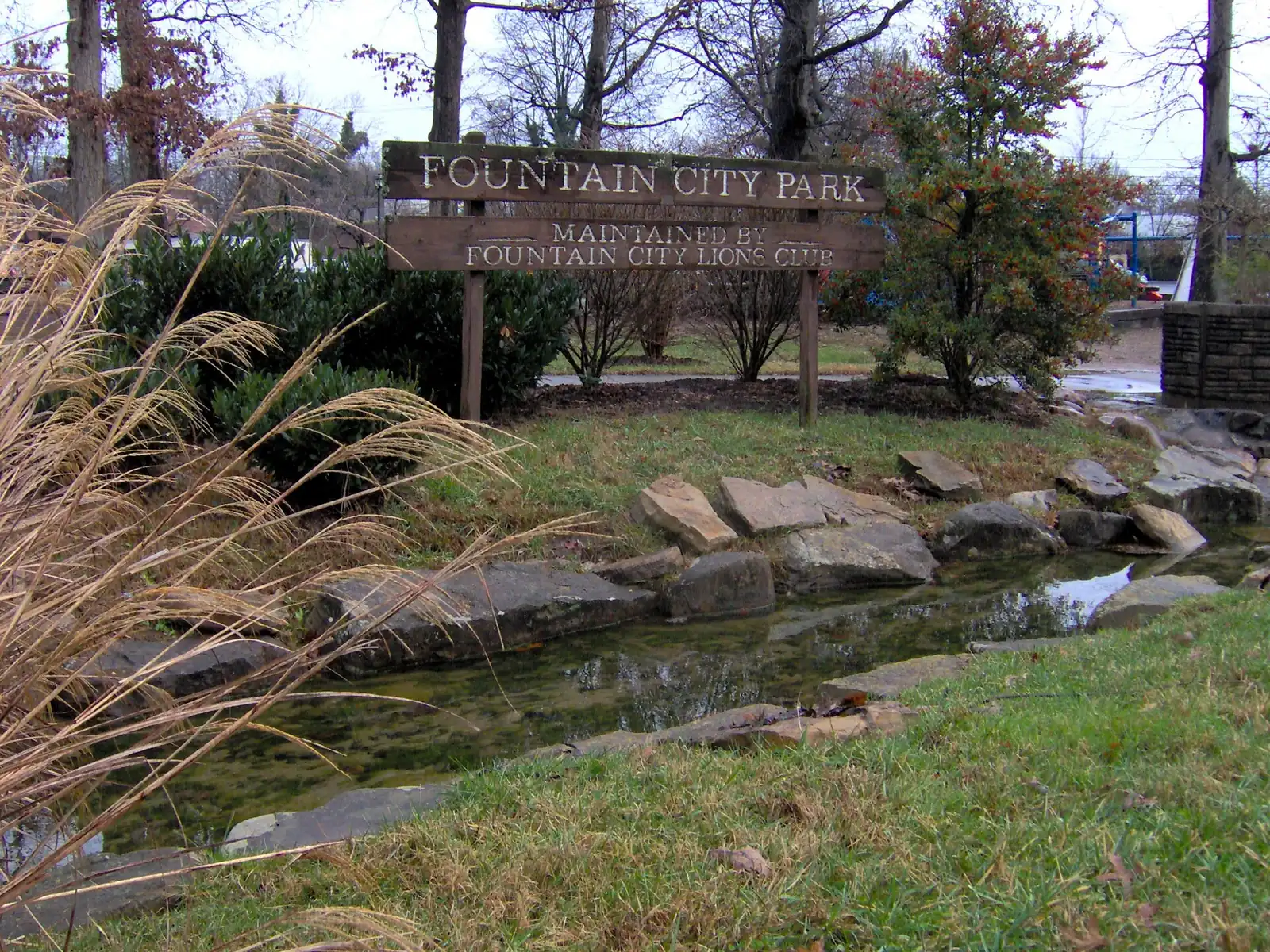 The Fountain City Park sign and stone-lined stream in North Knoxville; dogs are welcome on a leash in city parks.